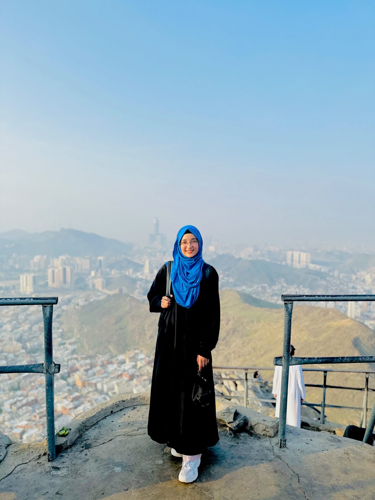 A sister on a mountain path above the city